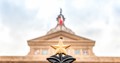 Photo looking up at the finial star atop the Texas Capitol Fence, with the top of the Capitol building in the background