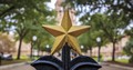Photo of a gold finial in the shape of a Texas star atop the gate in front of the Capitol building